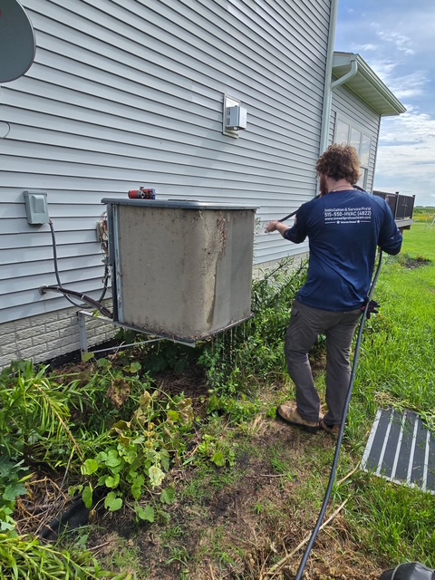 Technician cleaning an outdoor AC coil